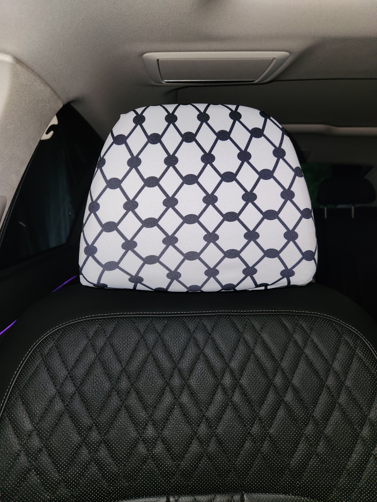 Close-up of Keffiyeh design on white headrest cover inside vehicle interior