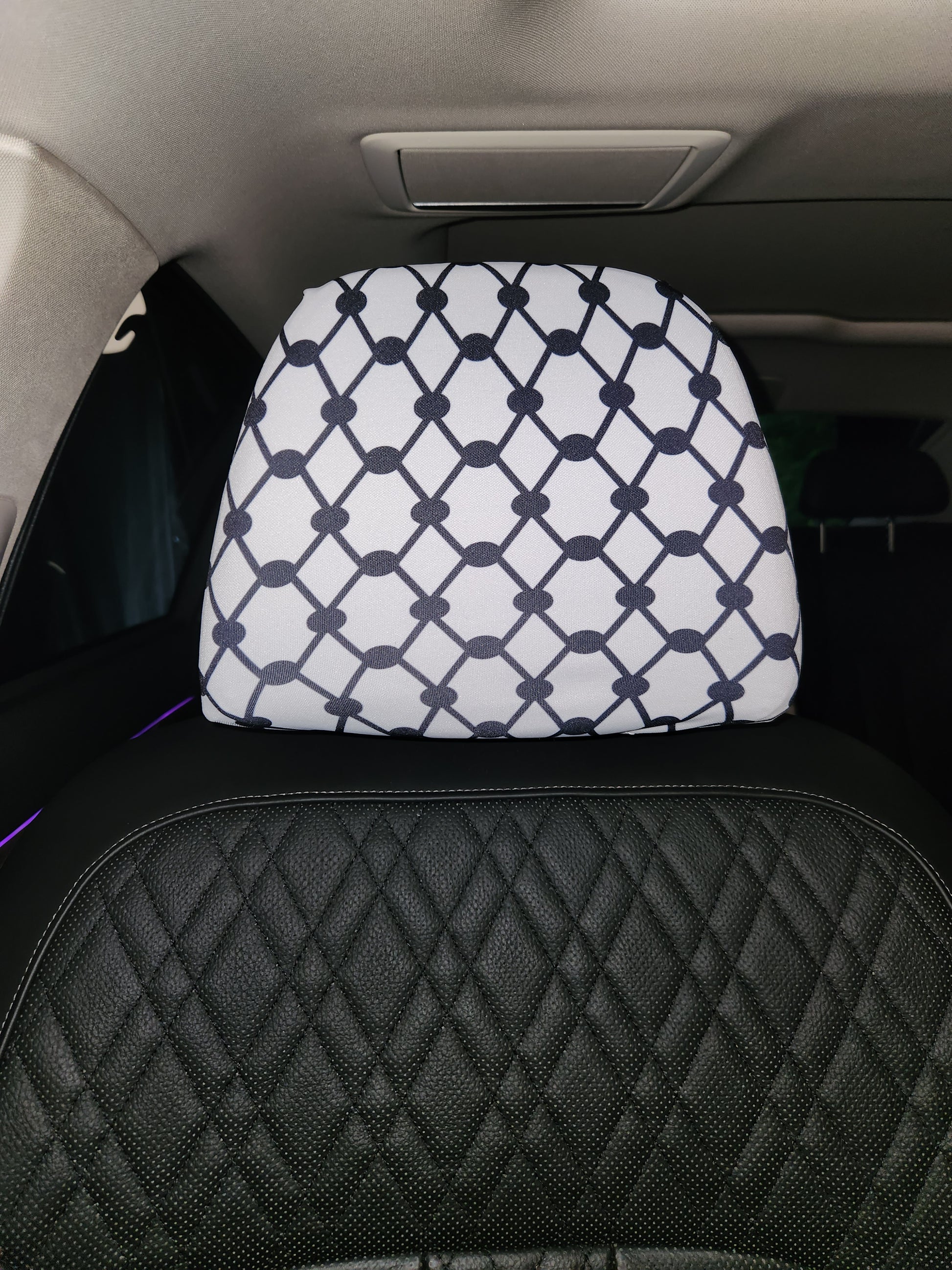 Close-up of Keffiyeh design on white headrest cover inside vehicle interior