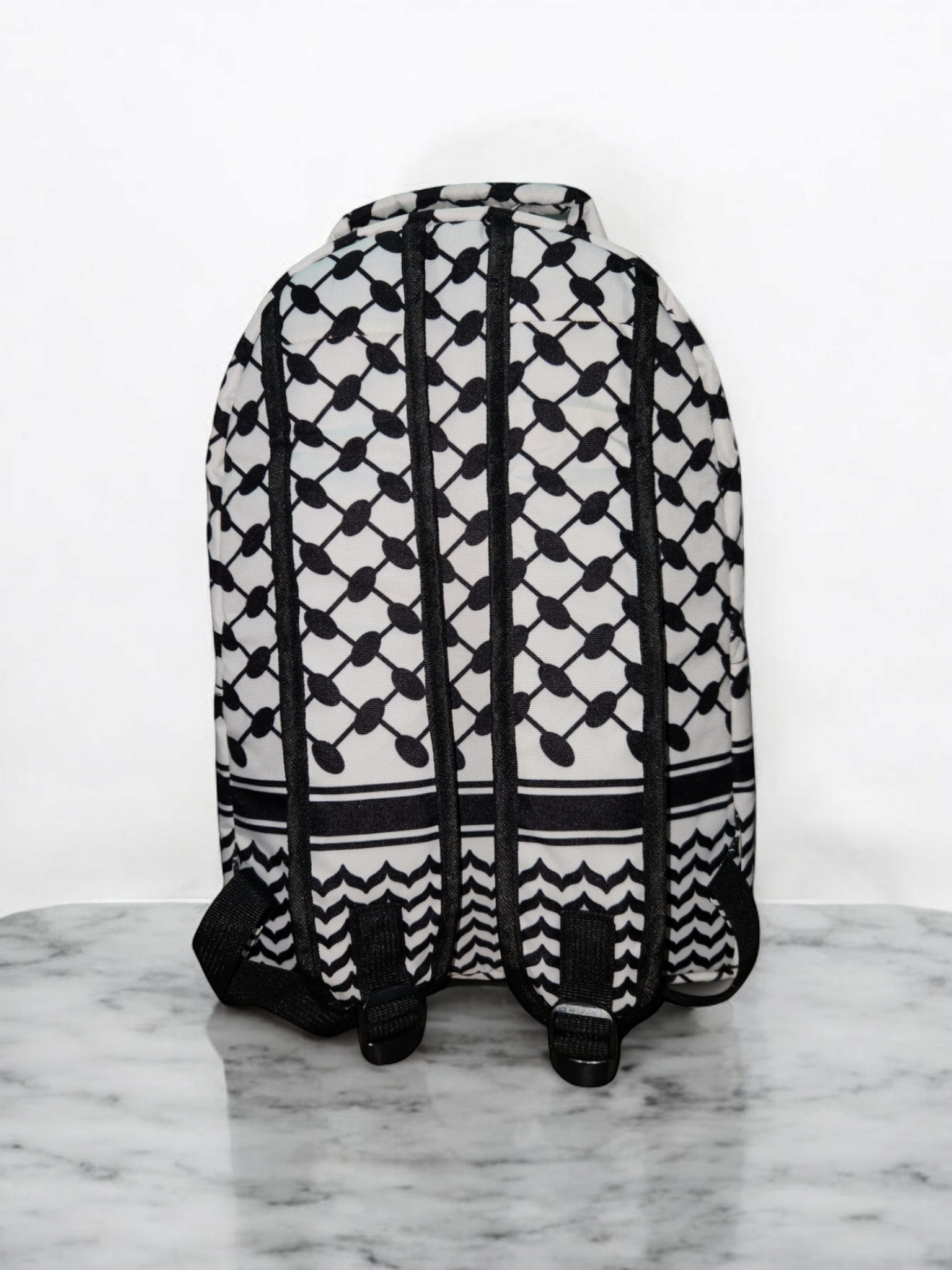 Back view of Palestinia FC Keffiyeh Backpack showing kufiya pattern and adjustable black straps on marble background