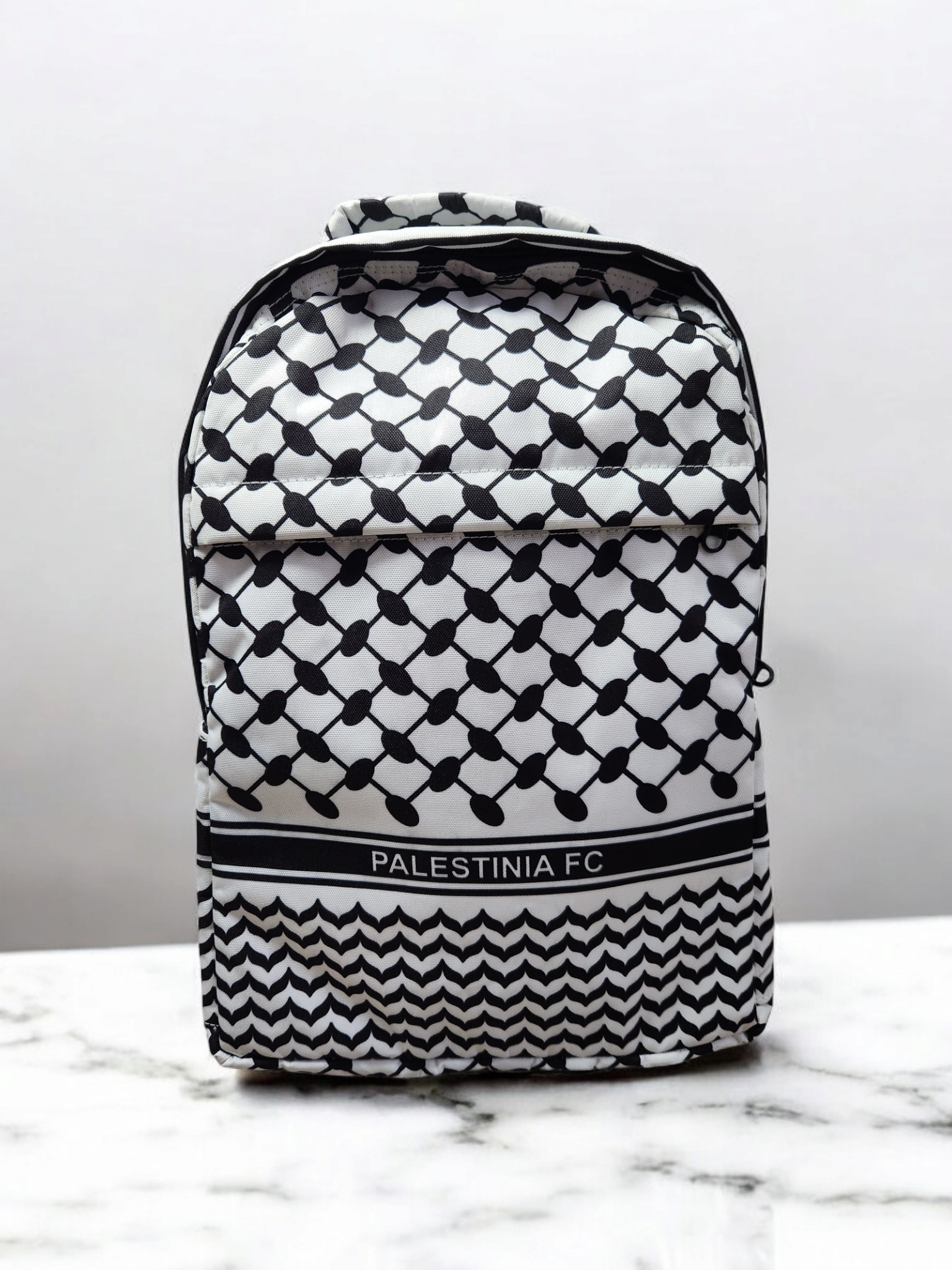 A backpack with a geometric pattern, predominantly in black and white, with 'PALESTINIA FC' branding on the lower part.