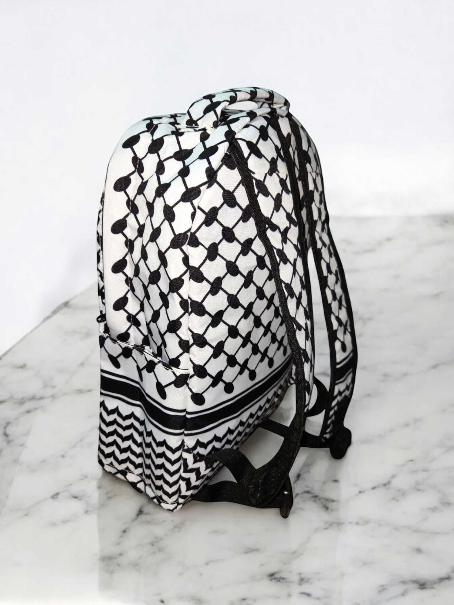 Side view of Palestinia FC Keffiyeh Backpack showing black and white kufiya pattern and adjustable padded straps