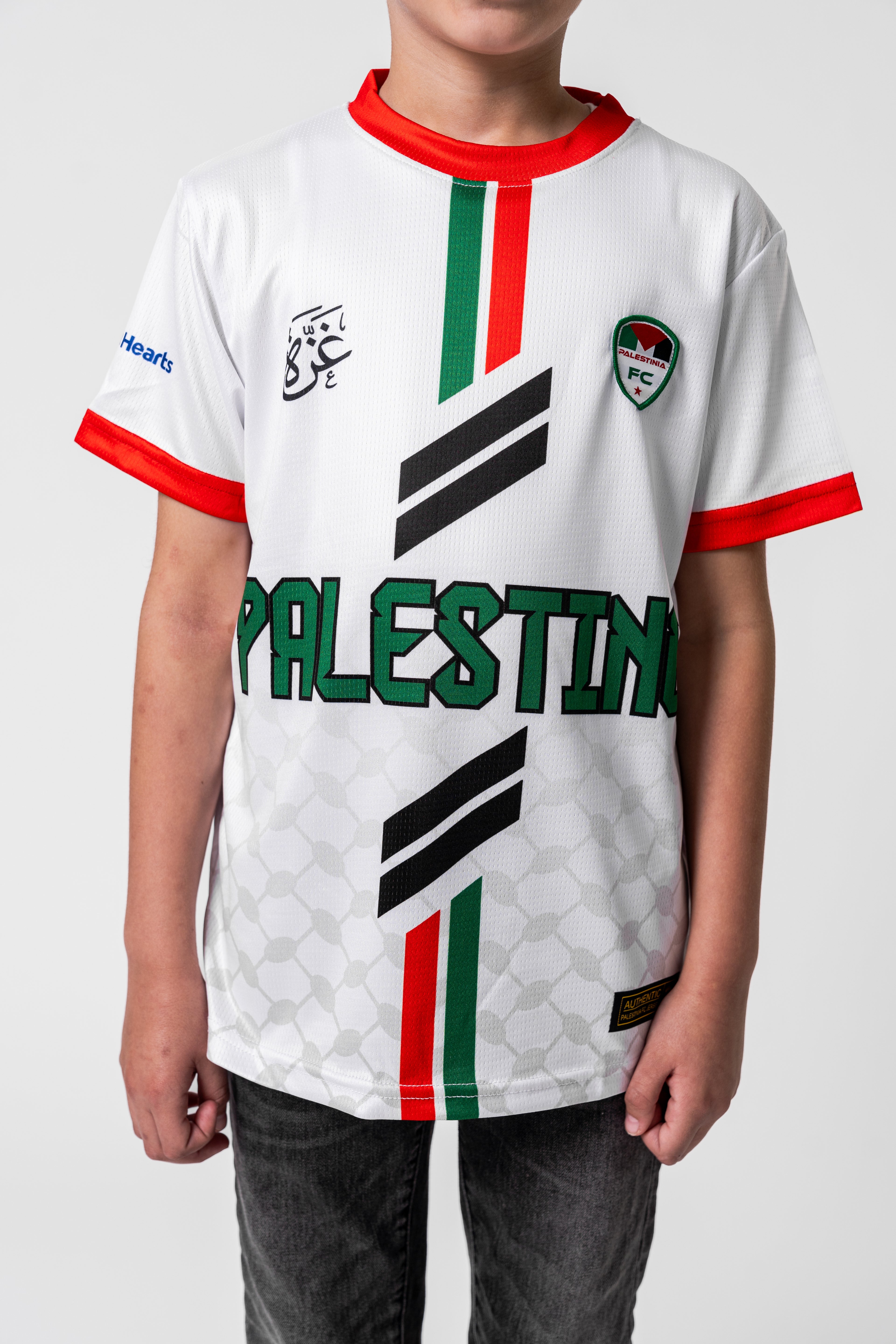 Child wearing a white sports jersey with 'Palestine' printed on it, featuring red, green, and black colors.
