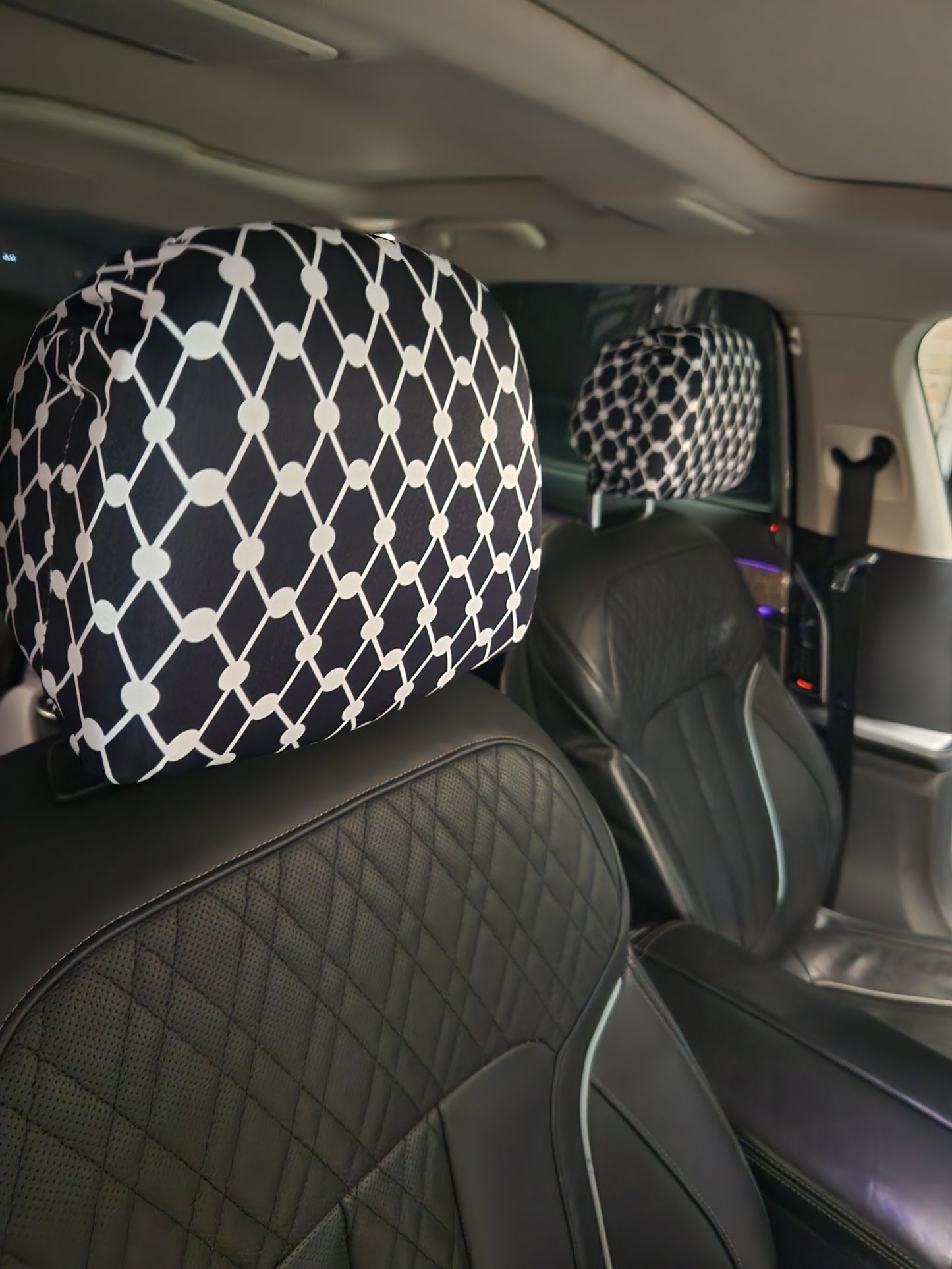 Black Kiffiyeh car headrest cover installed on leather seats, showing Palestinian Kufiya pattern