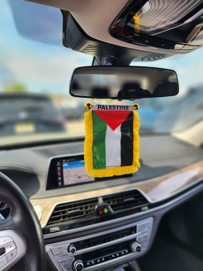 Palestine rearview mirror flag hanging in car interior with sunlight and dashboard view