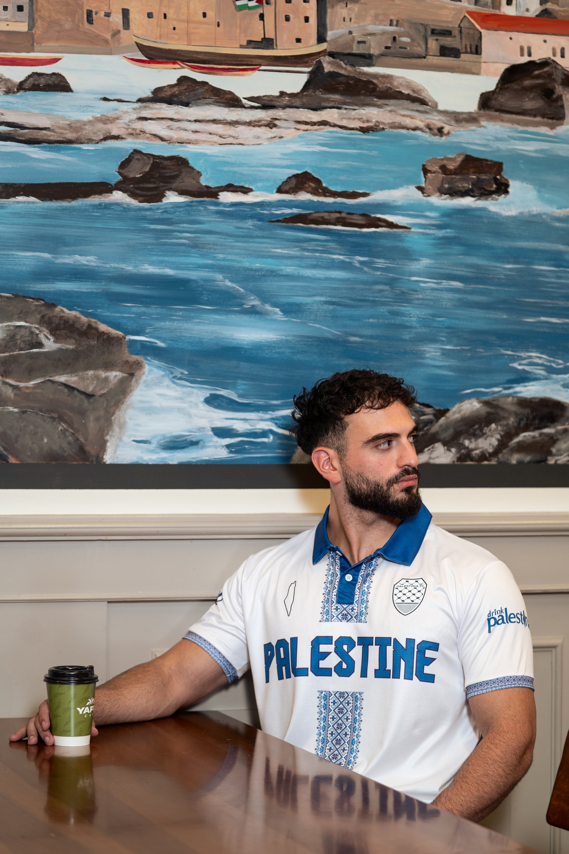 Model standing outdoors wearing white and blue Palestine jersey symbolizing heritage