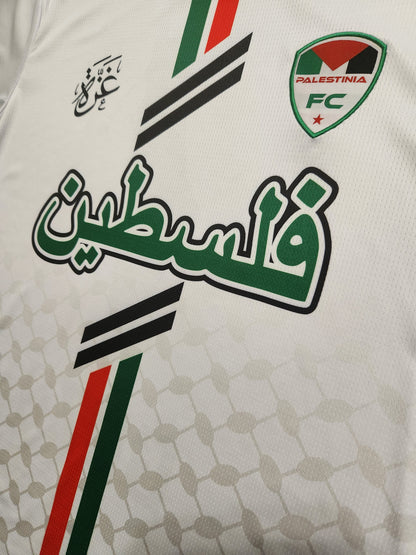 Close-up of Arabic text and Palestinia FC crest on white jersey with keffiyeh pattern