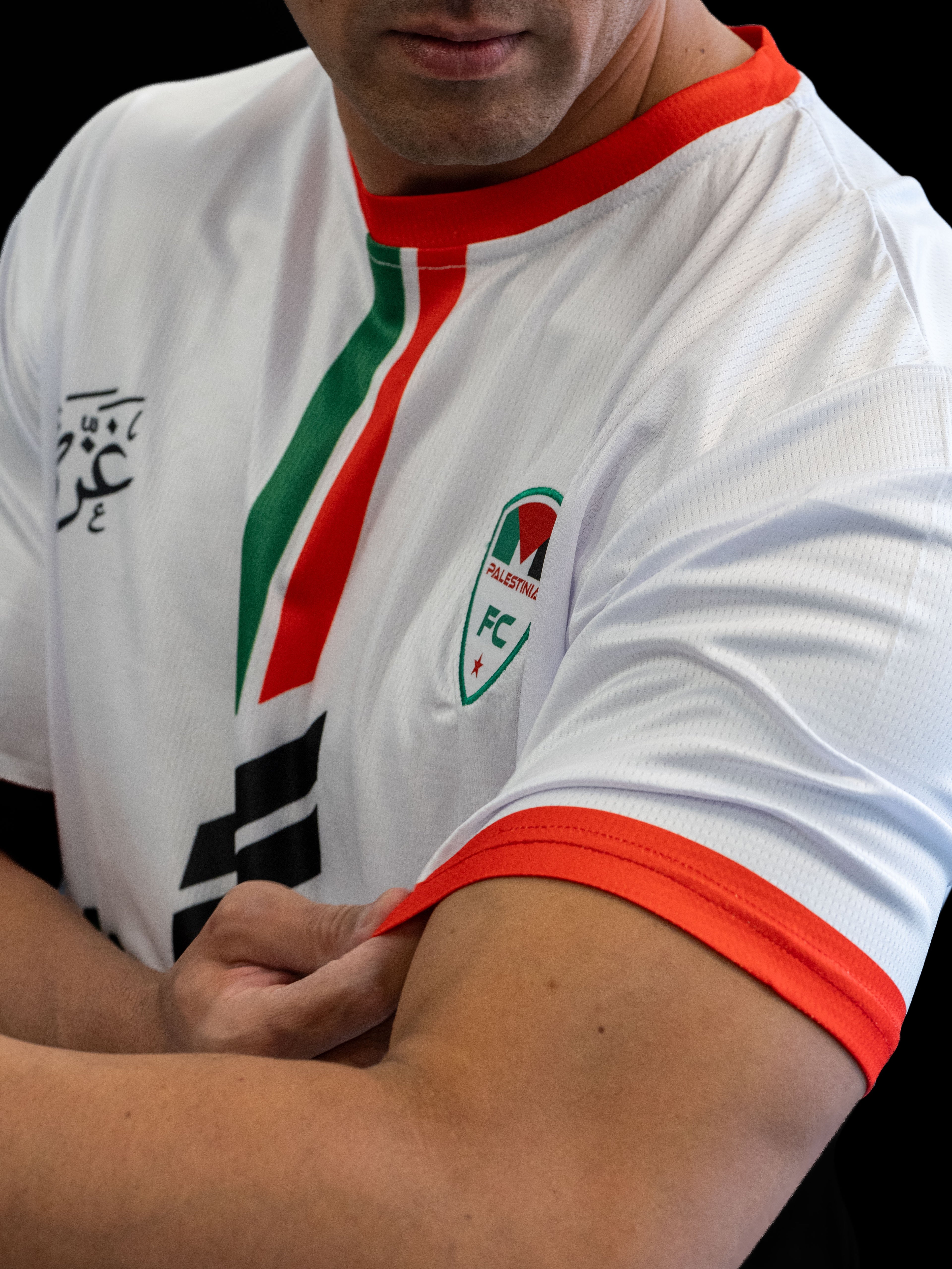 Model wearing White Palestine football jersey with red and green vertical stripes and Palestinia FC crest